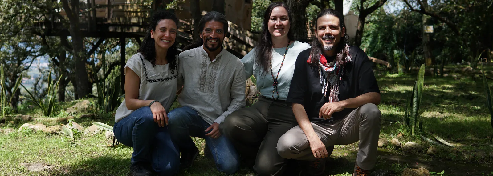 El equipo de Ayahuasca México, cuatro personas en cuclillas sobre el pasto, bajo los árboles