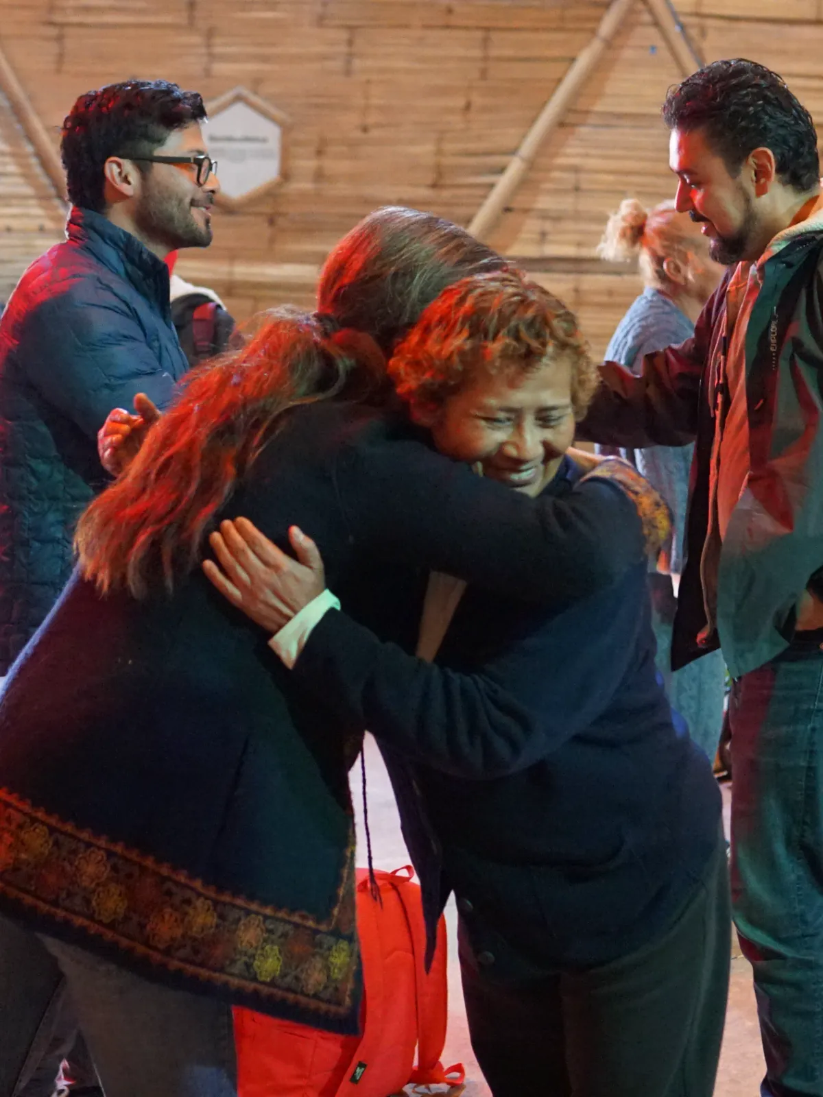 Dos participantes se abrazan al terminar la ceremonia, con el grupo alrededor