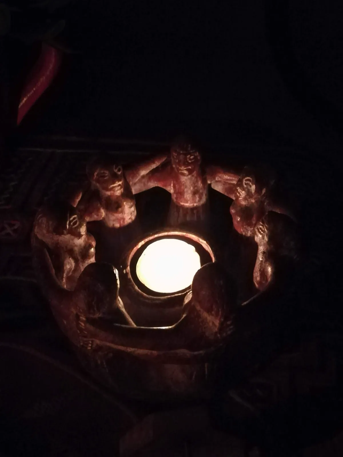 Una vela encendida dentro de un candelero de barro, en la oscuridad