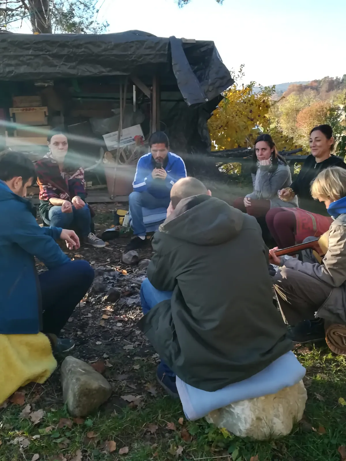 Grupo sentado en círculo al aire libre, conversando una mañana de otoño